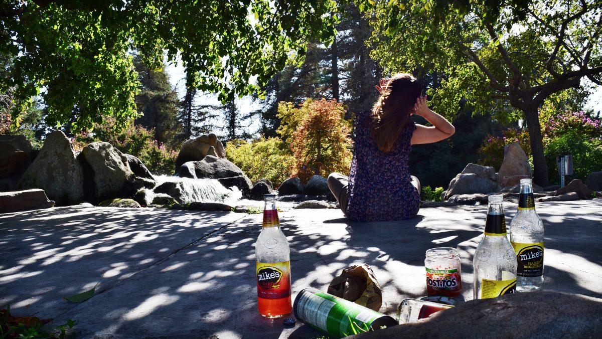 Signal Editor Brittney Valadez (Senior, Communication Studies) meditates at a favorite location of Stan State students, the fountain near the Stan State Amphitheater, Friday, Sept. 23, 2016. In the foreground, alcohol litter left by unknown parties, showcases the need for upcoming wellness workshops offered by the Psychological Counseling Services. (Signal photo/Oscar Copland)