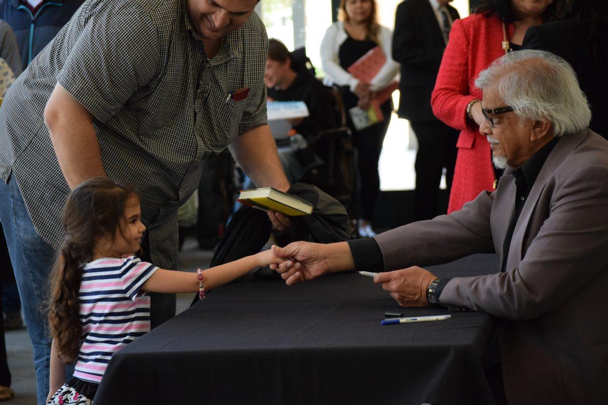 Dr. Gandhi shakes the hand of a child after his keynote address. (Signal Photo/Steph Landeros)