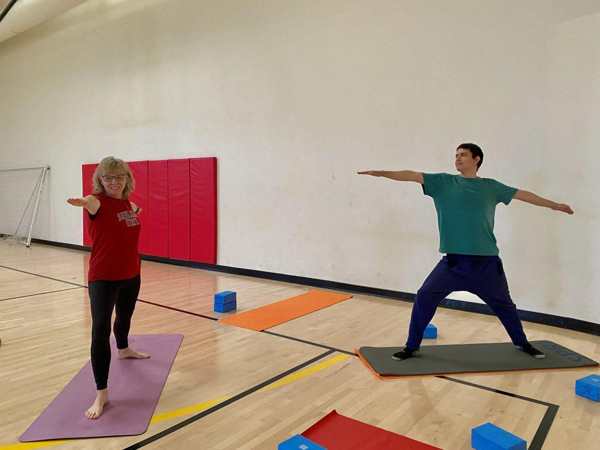 Susan Brumm (left side), with Stan State student Emmanuel Valenzuela (right side), doing the yoga pose called the Warrior II.