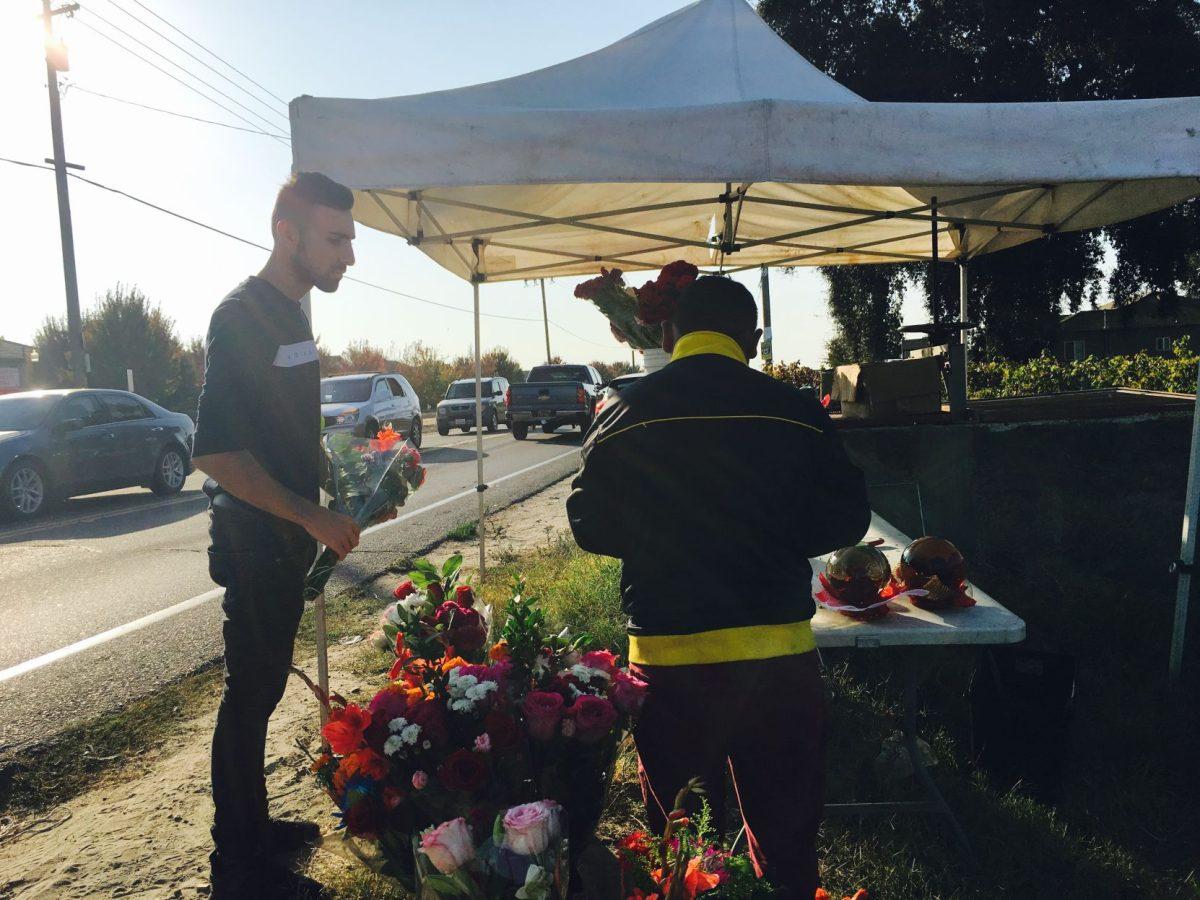 Canelo Reyes selling flowers to a client. (Signal Photo/Francely Santos)