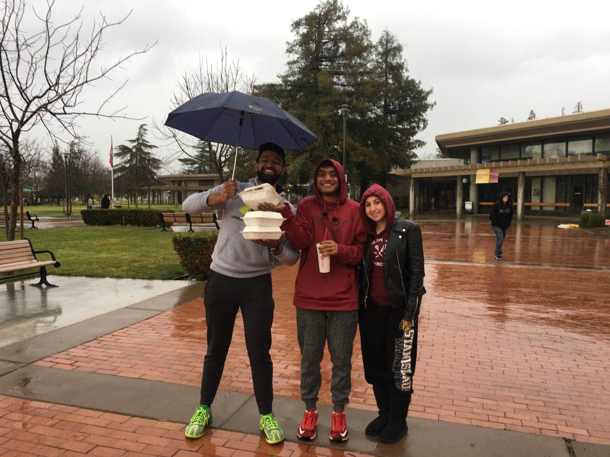 Students work together to keep their food dry on a rainy day. (Signal Photo/ Sarah George)