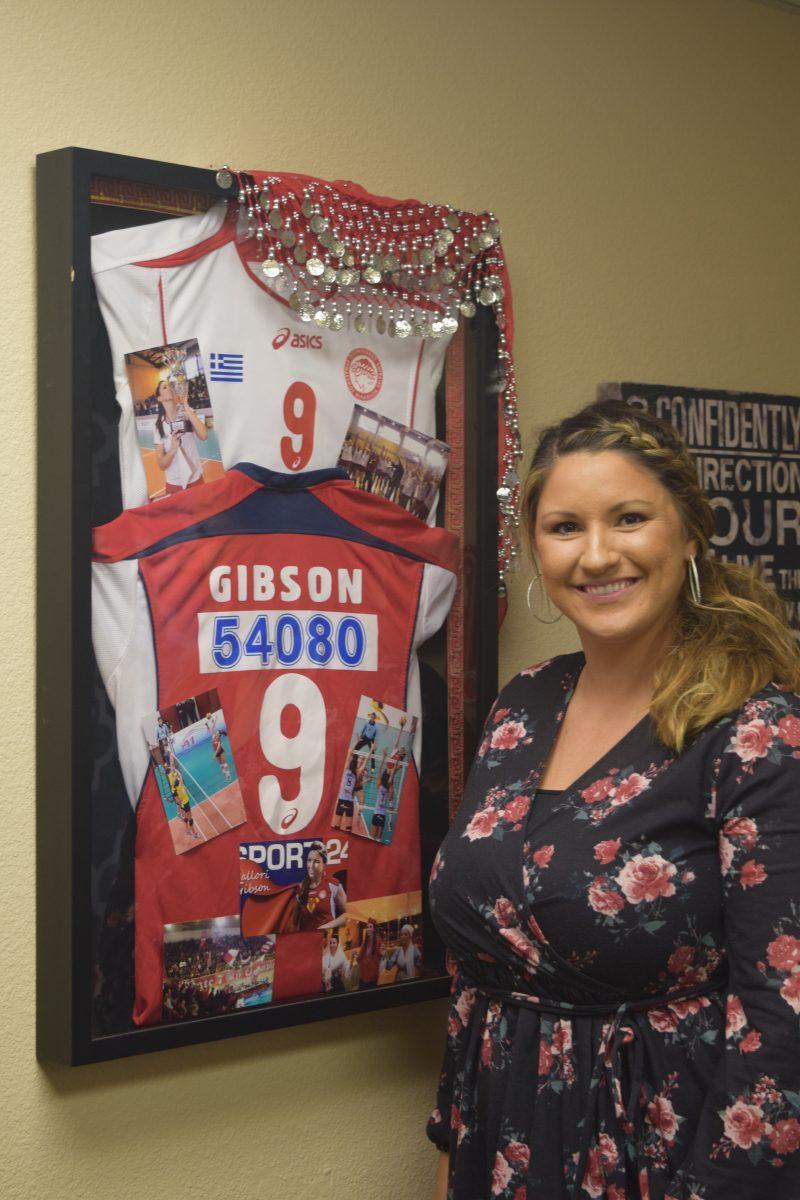 Coach Mallori posing with her jersey from playing professional volleyball in Greece.&#160;