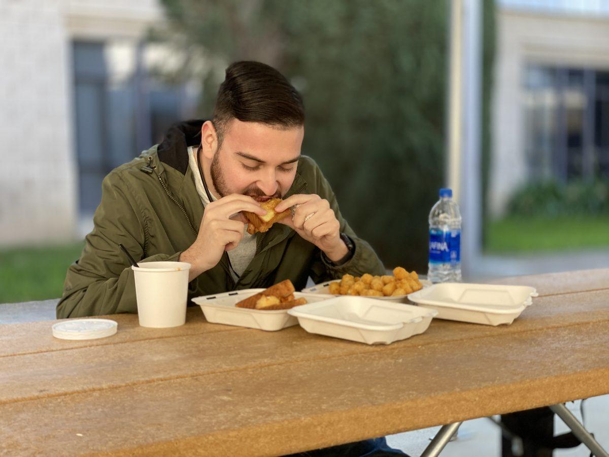 Anthony Ramirez (senior, History) eating an "Old Glory" sandwich, which includes Texas Toast with fried cheese curds, pepper jelly and bacon. He also tried out the tater-tots and tomato soup. (Signal Photo/ Randel Montenegro)