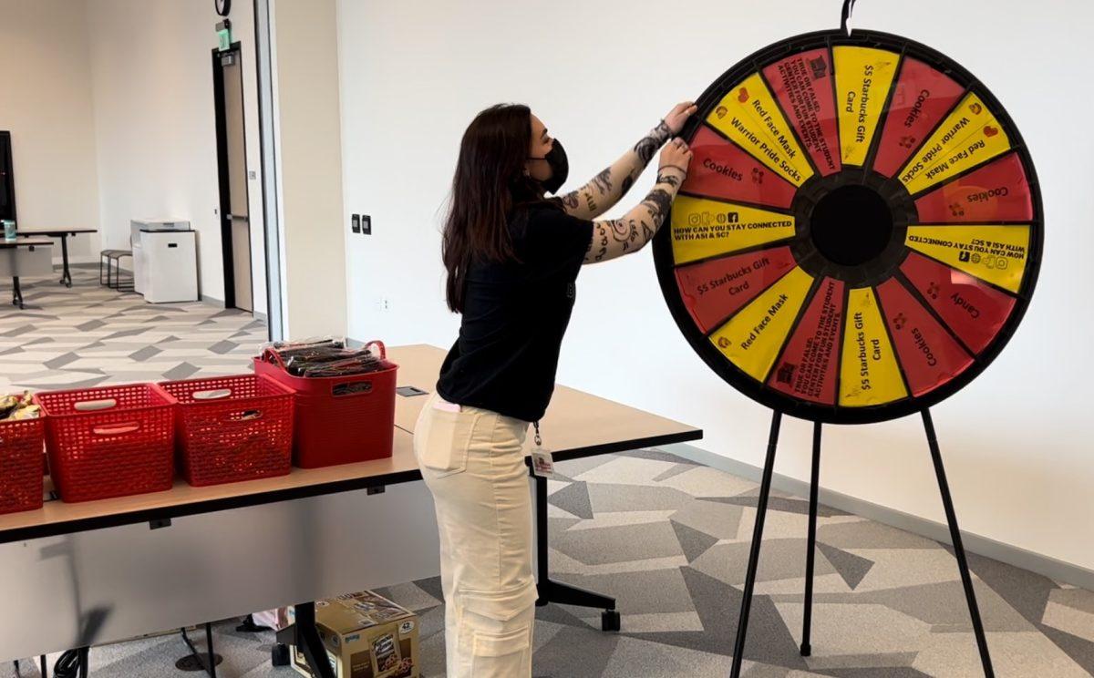 A student assistant spins a prize wheel during the Student Center Birthday Bash on March 3. 
