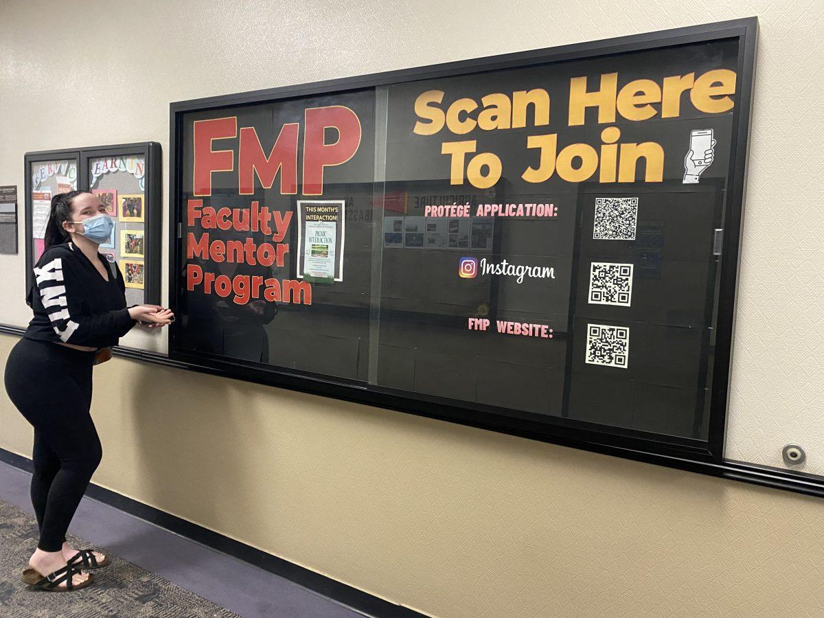 New FMP protege Alexis Ryan poses in front of the FMP bulletin, which is used to promote the program to the campus community.&#160;