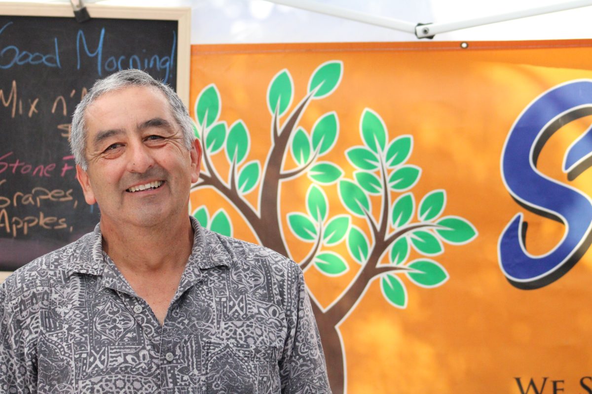 Augustine Martinez bearing a smile in front of his “Sweet Tree Farms” banner.