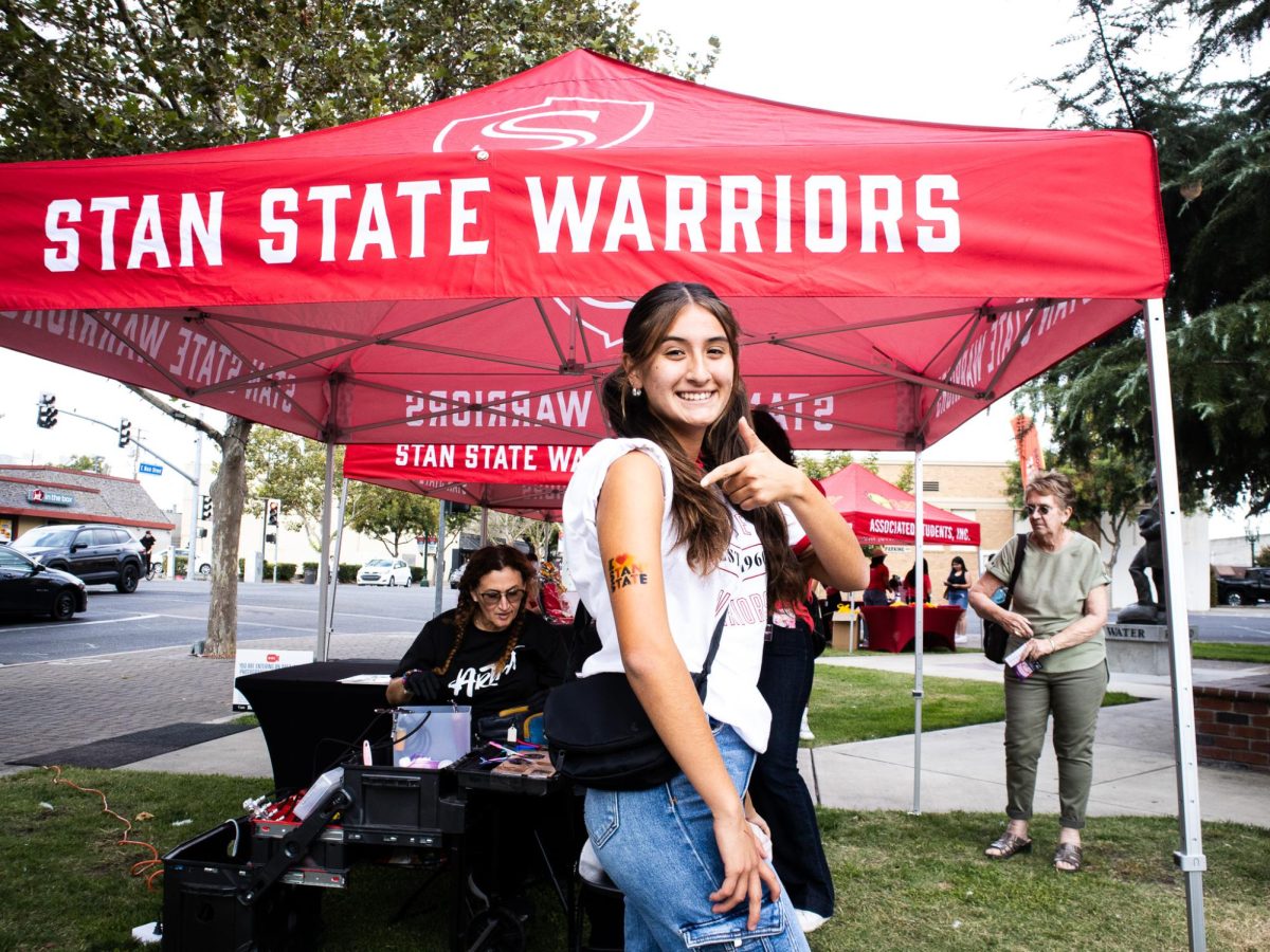 Yelena Ordonez (Kinesiology, sophomore) posing, showing her "I love Stan State" airbrush tattoo in Central Park.