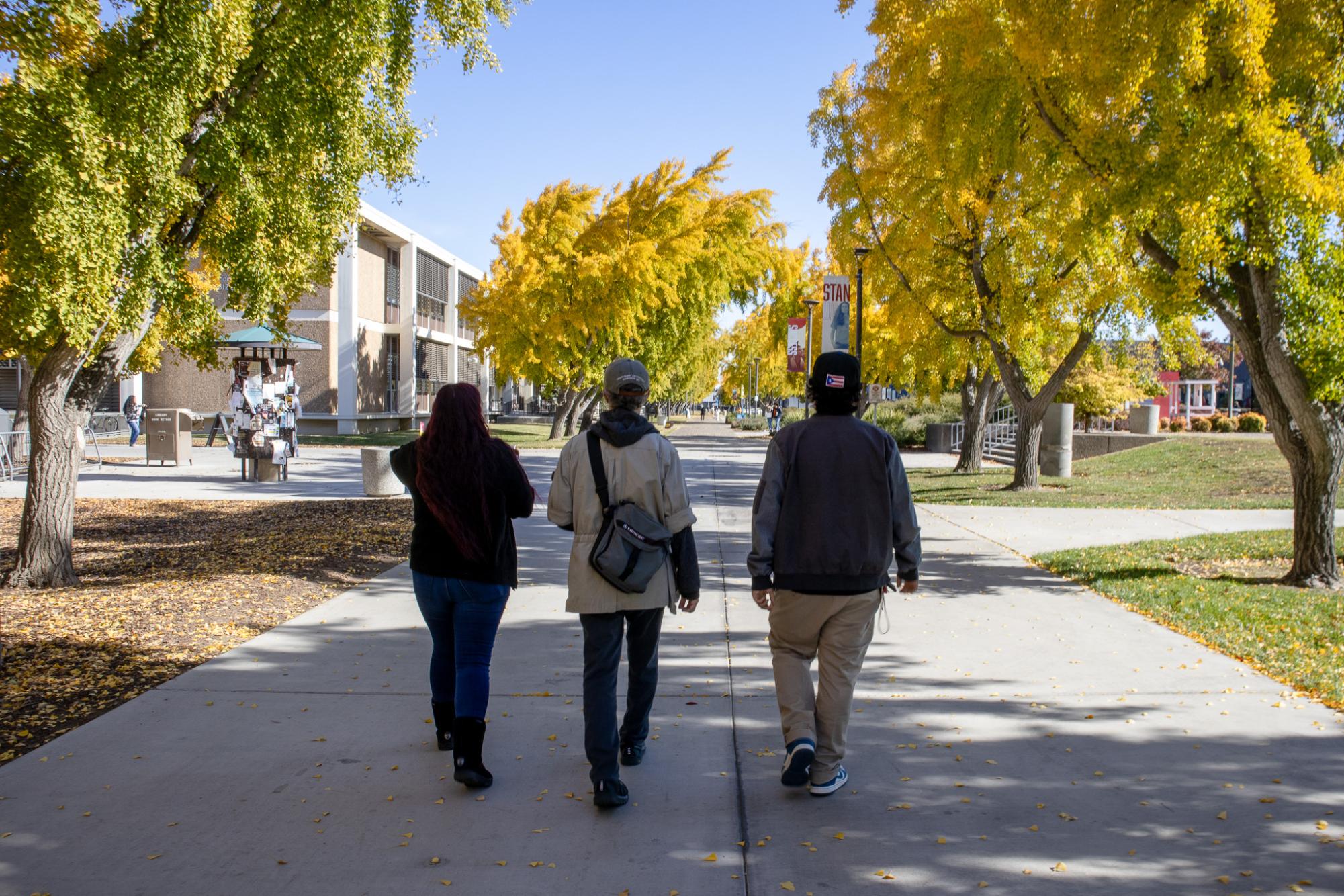 A view from behind (from left to right) Jasmin Ochoa, Jeff Jacoby and Robbie Herrera walking on campus near Bizzini Hall.