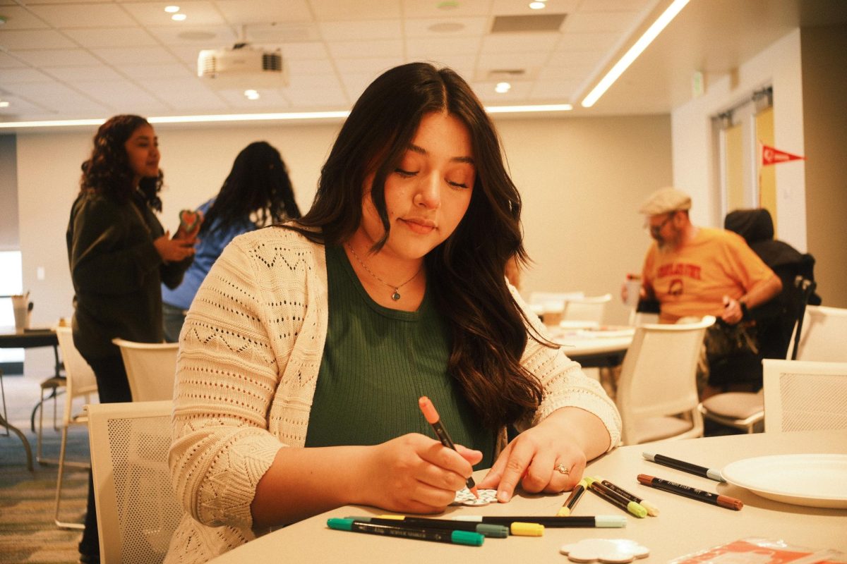 Calfresh Healthy Living Program Assistant Meghan Reyes paints her canvas magnet as she chats with students.