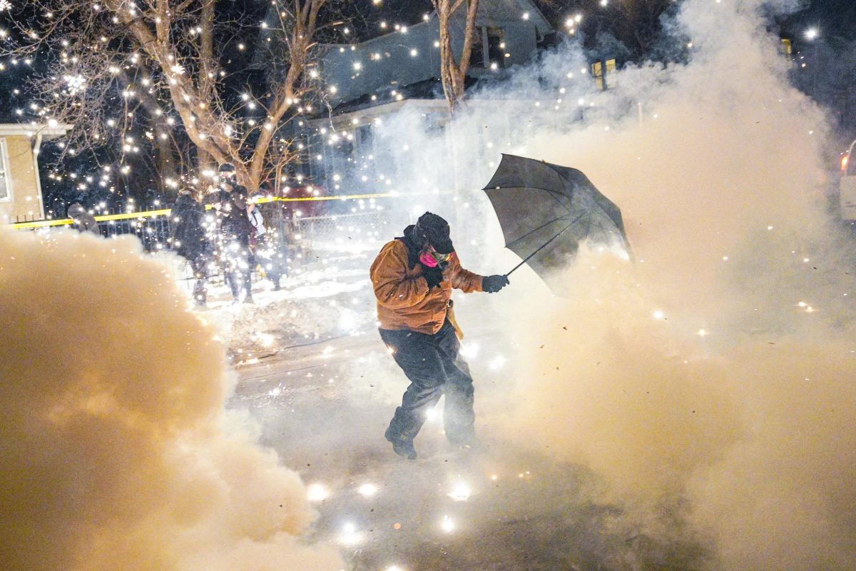 A protestor attempting to protect themselves as federal agents fire munitions and pepper balls