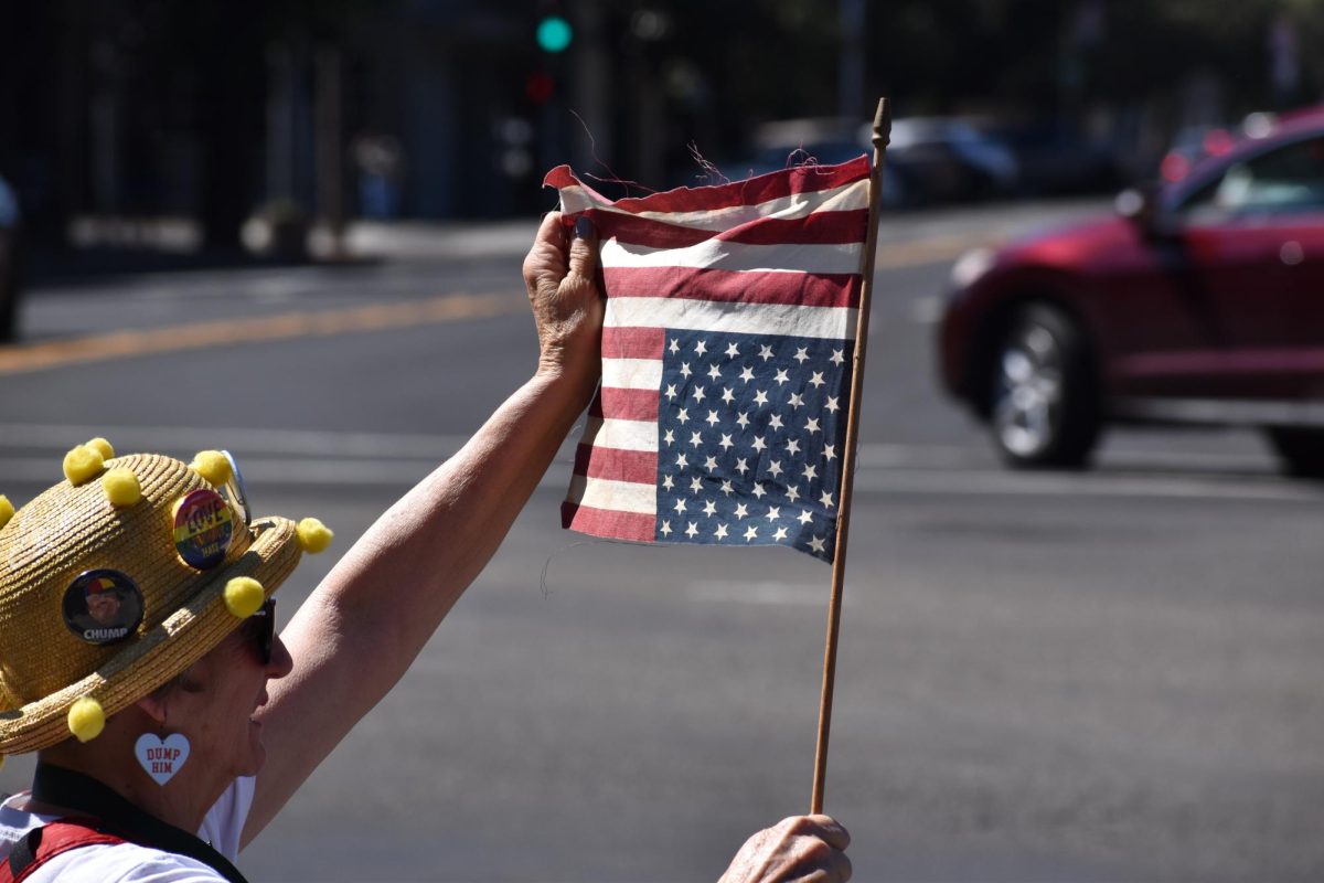 Protestor holds up an upside down American flag and shows it towards traffic on Saturday, March 28,  2026 at the No Kings Protest in Modesto.