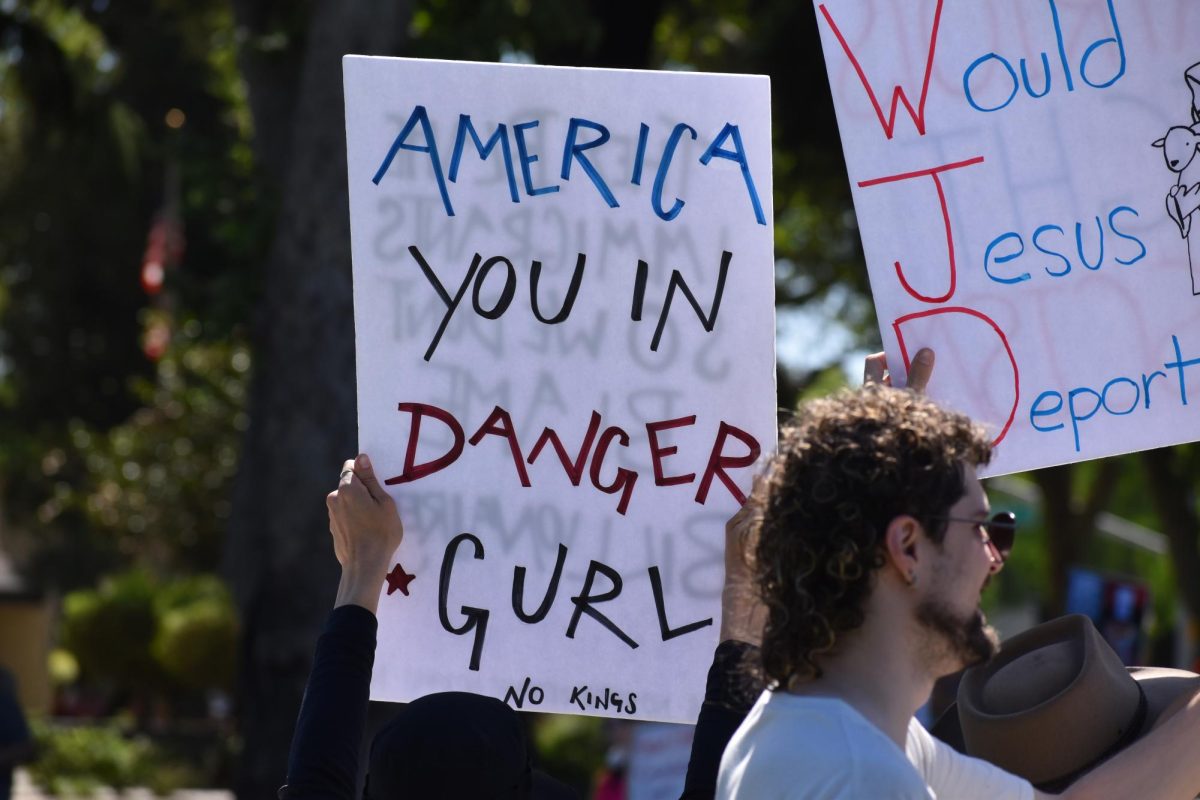 Protestors at Gracaeda hold up signs, one reading, "America you in danger gurl," on Saturday, March 28,  2026 at the No Kings Protest in Modesto.