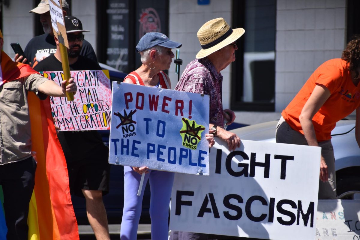 People gather on 5 point holding up signs and chanting towards oncoming traffic on Saturday, March 28,  2026 at the No Kings Protest in Modesto.