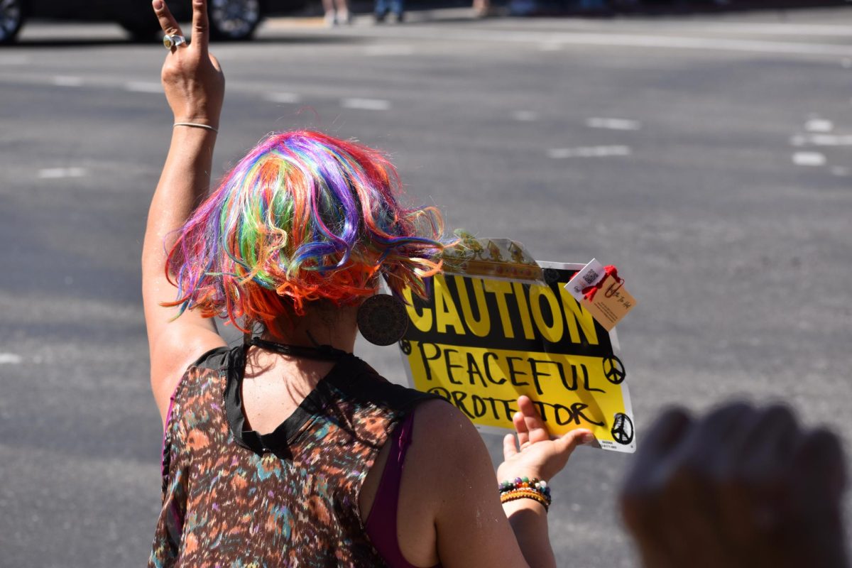 Protestor holds up a sign that reads "Caution, peaceful protestors," on Saturday, March 28,  2026 at the No Kings Protest in Modesto.